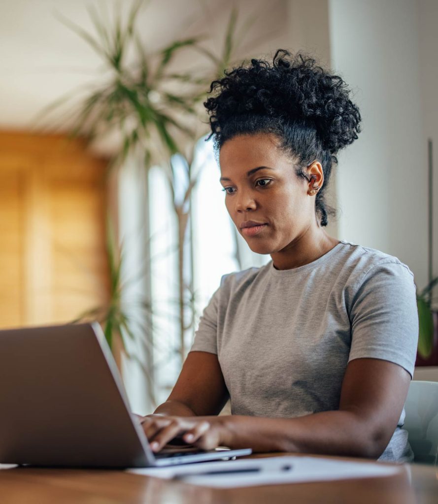 A woman at a table using a laptop.