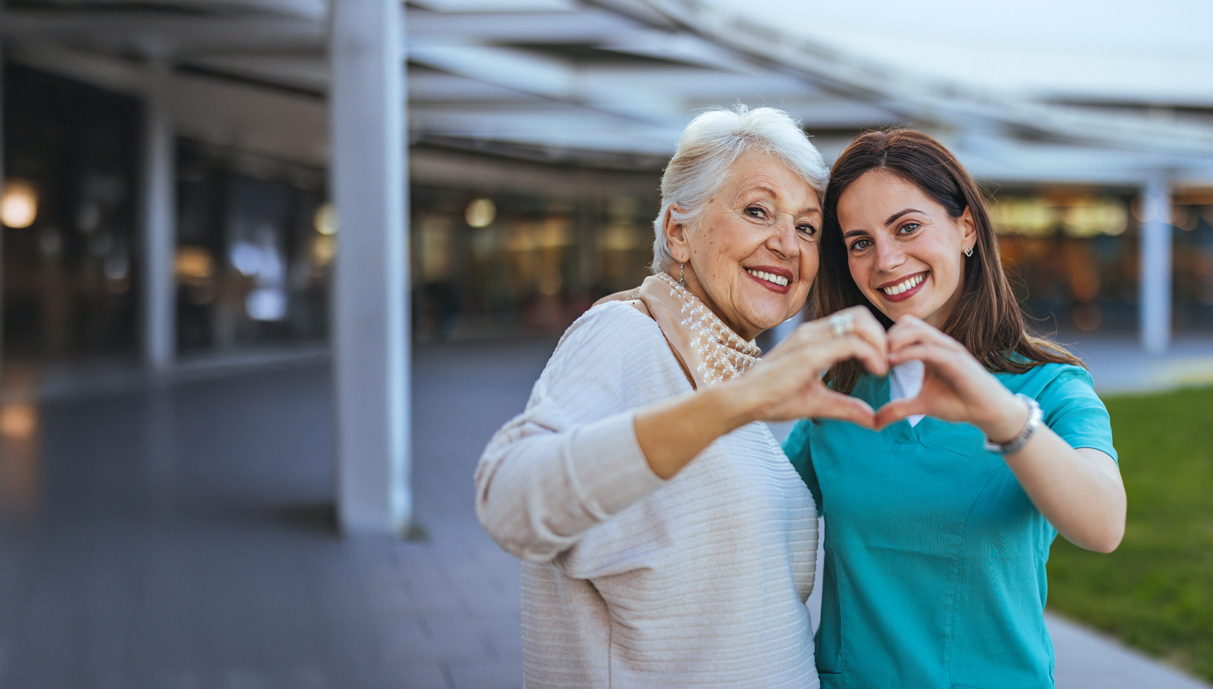 Senior lady with practitioner making a joint heart shape with their hands